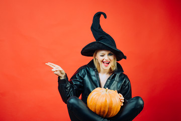 Funny face and Surprised woman. motional young women in halloween costumes on party over red background with pumpkin. Witch posing with Pumpkin.