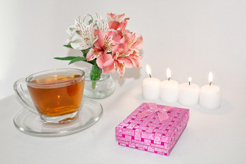 Image of a pink luxury gift box with a bouquet of beautiful Alstroemeria flowers, a romantic candle and cup of tea, a festive still life. Greeting card concept.