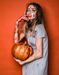 Halloween girl vampire with bloody pumpkin. Beautiful Young woman as sexy vampire in blue dress -...