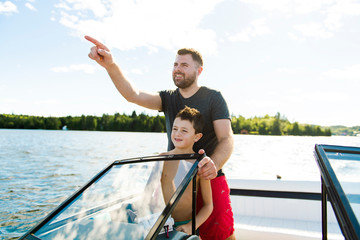 Man driving boat on holiday with his son kid