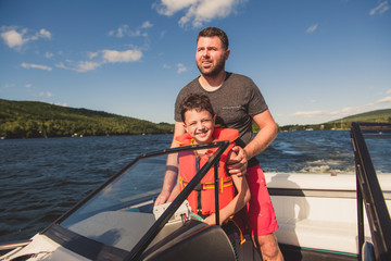 Man driving boat on holiday with his son kid