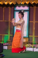 The lady in Middle thai classical dancing suit is showing pattern of traditional dancing on platform.