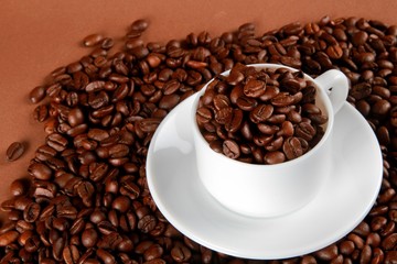 Mug full of, and surrounded by, coffee beans