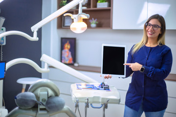 Young and beautiful dentist holds in his hand modern digital tablet device