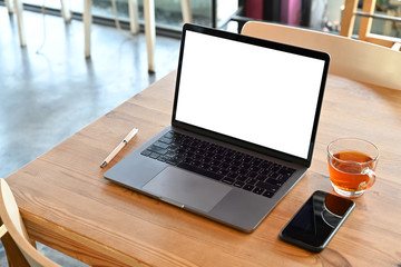 Mockup blank screen laptop on wooden table in cafe.