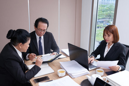 Team of professional Vietnamese lawyers working with documents at table in office