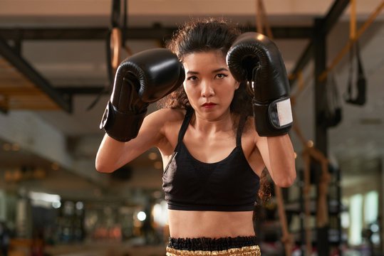 Portrait of active young Asian woman wearing boxing gloves