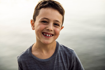 Outdoor portrait of adorable child boy next to lake at the sunset
