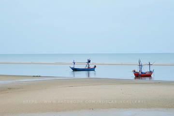 Boat on sand at sea beach in tropical resort on blue sky background. Summer vacation, recreation, travelling concept.