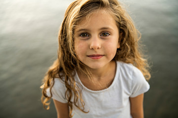 Cute child girl on a wooden platform by the lake.