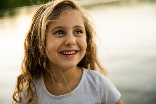 Cute child girl on a wooden platform by the lake.