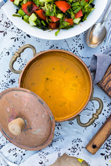 Hot creamy pumpkin curry soup with vegetable coconut cream milk and cauliflower pieces in vintage copper pot as vegan lunch or vegetarian dinner. Healthy food
