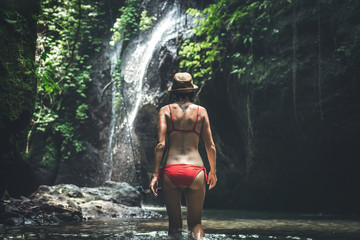 Young woman backpacker looking at the waterfall in jungles. Ecotourism concept image travel girl. Bali island.