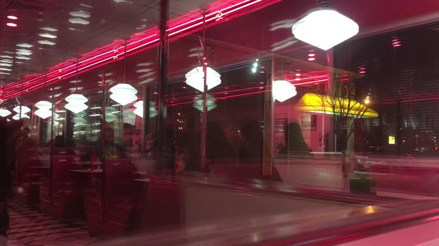 Diner reflection that's out of focus and blurred shows waitress taking order from table with other customers and tables in background. 