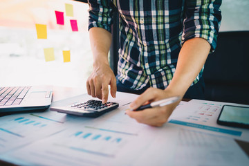 Businessman using calculator and laptop computer for calculating with finance paper, tax, accounting. Finance concept..