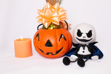 Postcard for Halloween, pumpkin with candies and a ghostly monster doll and a lighted candle. On a white background.