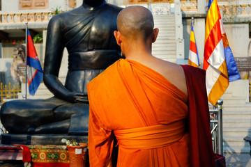 monk doing meditation in front of a statue of buddha