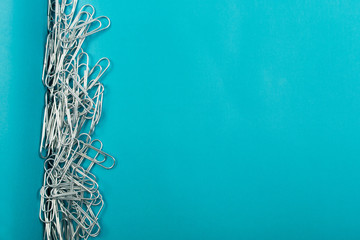 Heap of note paper clips on blue background top view