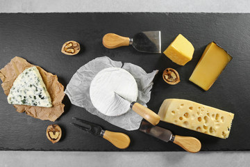 Different kinds of cheeses camembert, brie, parmesan, blue cheese captured from above top view . Black chalkboard as background. Layout with free text space