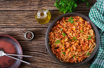 Spaghetti bolognese pasta with tomato sauce, vegetables and minced meat - homemade healthy italian pasta on rustic wooden background. Top view. Flat lay