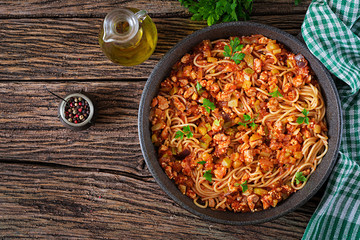 Spaghetti bolognese pasta with tomato sauce, vegetables and minced meat - homemade healthy italian pasta on rustic wooden background. Top view. Flat lay