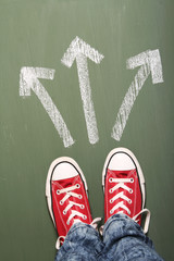 Young person standing in front of three arrows showing different ways