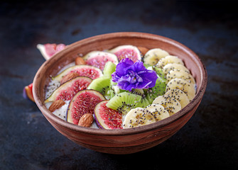 Delicious and healthy oatmeal with figs, kiwi, banana, almond and chia seeds. Black background. Healthy breakfast. Fitness food.