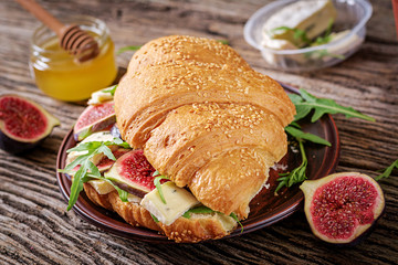 Fresh croissant sandwich with  brie cheese arugula and figs. Delicious breakfast.  Tasty food.