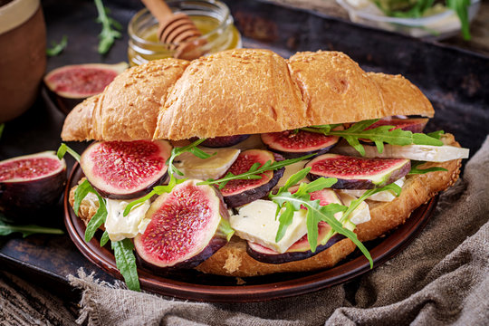 Fresh croissant sandwich with  brie cheese arugula and figs. Delicious breakfast.  Tasty food.