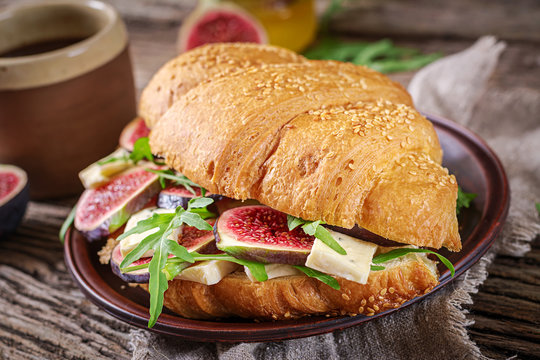 Fresh croissant sandwich with  brie cheese arugula and figs. Delicious breakfast.  Tasty food.