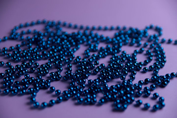 On a pink background are blue beads. Christmas concept. Cropped shot, isolated, macro, background, horizontal, isolated, blurred. Place for text.