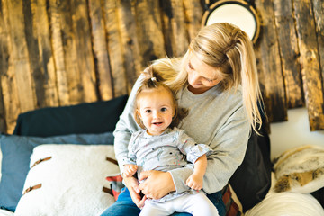 Mother and his baby daughter on bed having fun