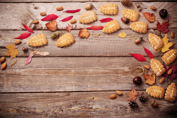 cookies and autumn leaves on  wooden background