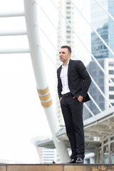 businessman looking away while standing outdoors with cityscape in the background