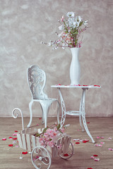 Wedding decorations. Rose petals, a beautiful white table and a chair in the interior. The room of the bride. Card