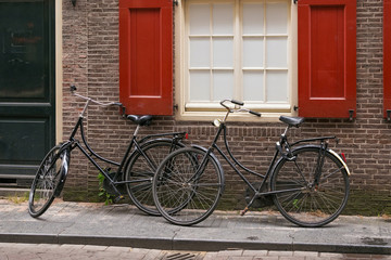 Fototapeta na wymiar Two old black bicycles near red brick wall in the center of Amsterdam, Netherlands.