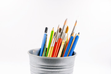 Fototapeta premium colored pencils and brushes to draw in jar, background