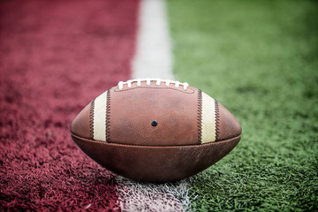 Closeup of an American Football resting on the goal line at a football stadium. Looks like its a touchdown.