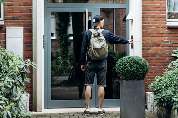 The tourist rings the doorbell to check in to the room he has booked or the student with the...