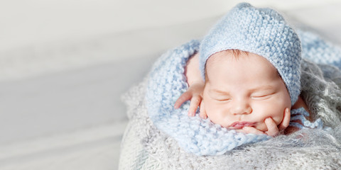 Sweet newborn baby sleeps.  Newborn boy folded handles  in a basket. Close up image. Copyspace