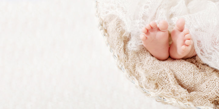 Newborn baby feet on knitted plaid. Closeup picture. Copy space
