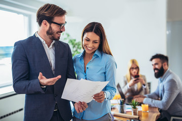 Portrait of two young businesspeople while colleague in background