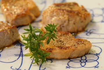 Gebratene Schweinemedaillons angerichtet mit einem Rosmarinzweig auf einem Teller