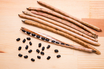 木のテーブルの上の黒小豆のさやと豆