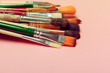 Obraz premium Set of art paint brushes over pastel pink background. Painting supplies, art concept