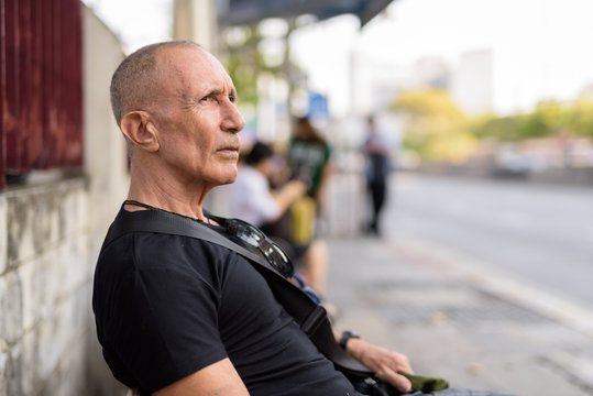Profile view of bald senior tourist man thinking while waiting a