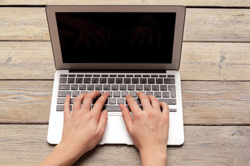 Fototapeta premium Female hands typing on a laptop keyboard top view