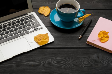 Office table with blank notebook and laptop / Coffee cup