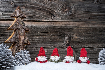 4 Weihnachtsmänner im Advent vor Holzwand