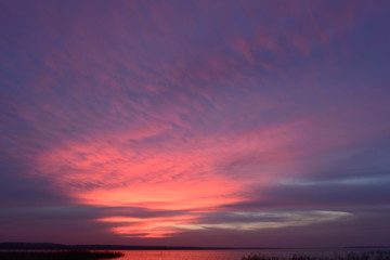 Autumn picturesque the twilight sky in the bright glowing colors of the sunset above the water surface of the lake